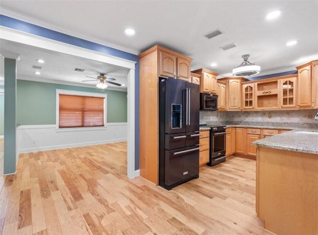 kitchen with light stone counters, ornamental molding, high end black refrigerator, and range with electric stovetop