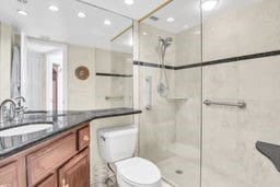 bathroom with toilet, vanity, and a tile shower