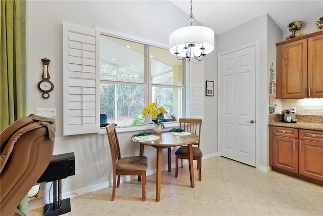 tiled dining room featuring lofted ceiling and an inviting chandelier