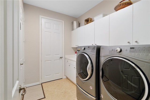 clothes washing area featuring washing machine and clothes dryer and cabinets