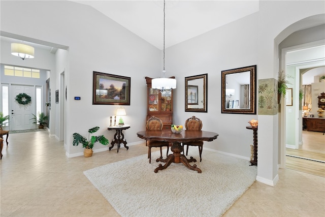 tiled dining area with high vaulted ceiling and a chandelier