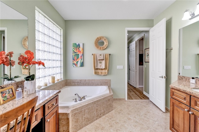 bathroom with tile patterned floors, tiled tub, and vanity