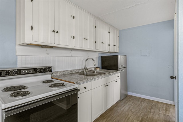 kitchen with stainless steel refrigerator, white cabinetry, sink, light hardwood / wood-style flooring, and electric range