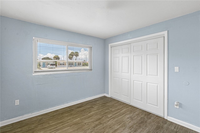 unfurnished bedroom featuring dark hardwood / wood-style flooring and a closet