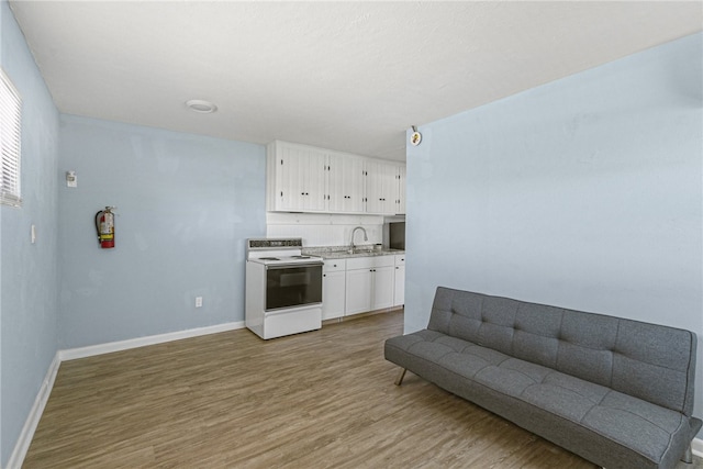 681 S Orlando Ave, Cocoa Beach, FL 32931 - kitchen featuring electric range, a sink, light wood-style floors, white cabinets, and baseboards