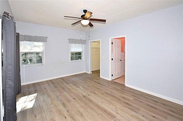 empty room featuring ceiling fan, a textured ceiling, and light hardwood / wood-style flooring