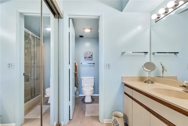 bathroom featuring hardwood / wood-style flooring, vanity, toilet, and an enclosed shower