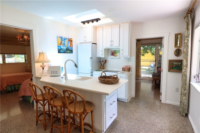 kitchen featuring white cabinetry, white appliances, a kitchen breakfast bar, and kitchen peninsula