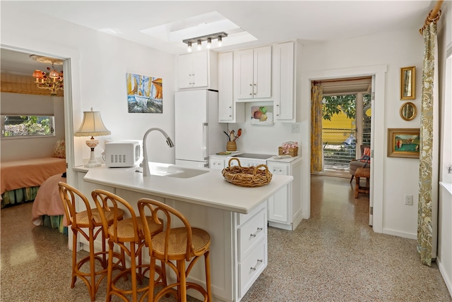 kitchen with an inviting chandelier, sink, a kitchen breakfast bar, white cabinets, and white appliances