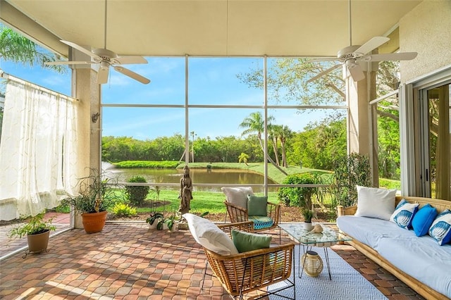 sunroom with a wealth of natural light, ceiling fan, and a water view