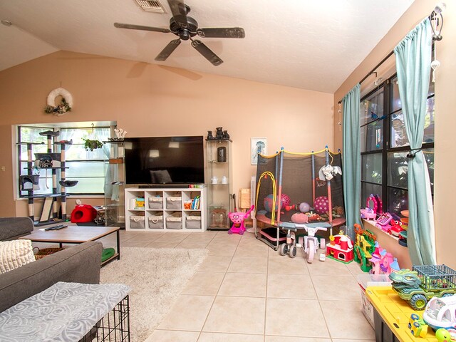 recreation room with ceiling fan, tile patterned floors, and vaulted ceiling