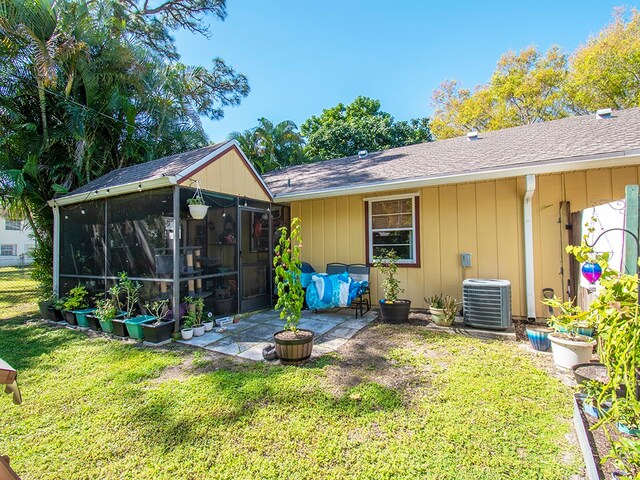 rear view of property featuring central air condition unit, a sunroom, a yard, and a patio area