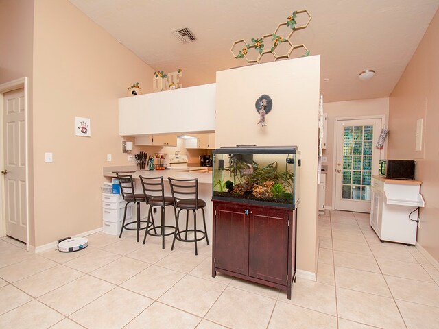 kitchen featuring a kitchen breakfast bar, white electric range, kitchen peninsula, and light tile patterned floors