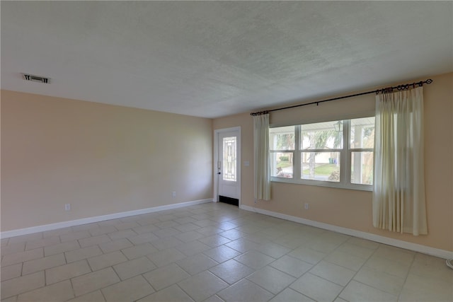 tiled empty room with a textured ceiling