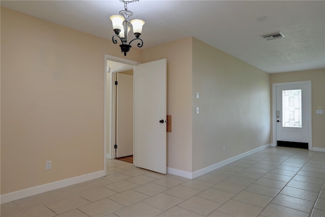 empty room with an inviting chandelier and light tile patterned floors