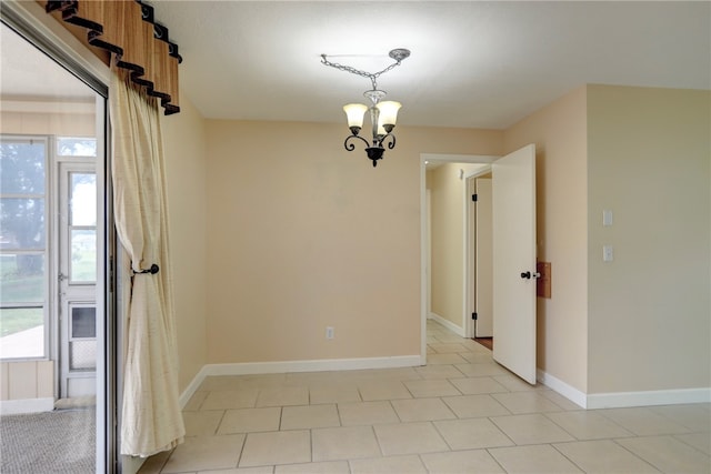 tiled empty room featuring a notable chandelier