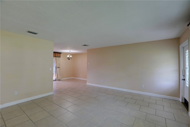 spare room featuring light tile patterned floors and an inviting chandelier