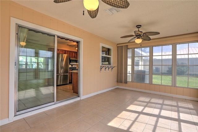 unfurnished sunroom with ceiling fan