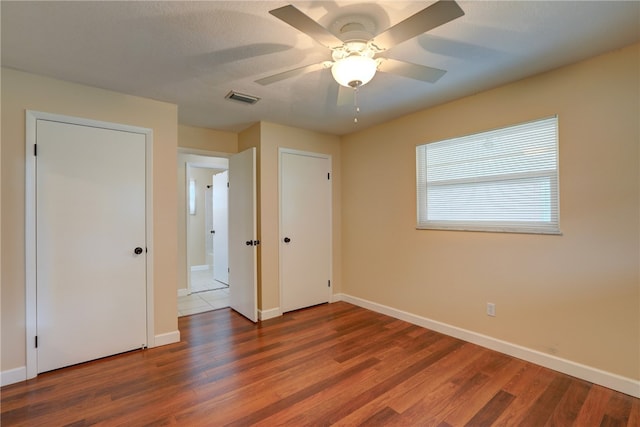 unfurnished bedroom with dark wood-type flooring and ceiling fan