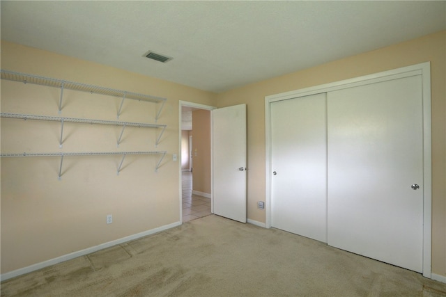 unfurnished bedroom with light colored carpet and a closet