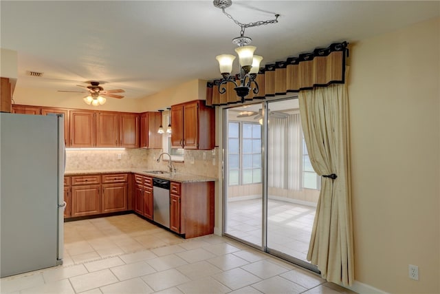 kitchen with ceiling fan with notable chandelier, stainless steel appliances, hanging light fixtures, sink, and backsplash