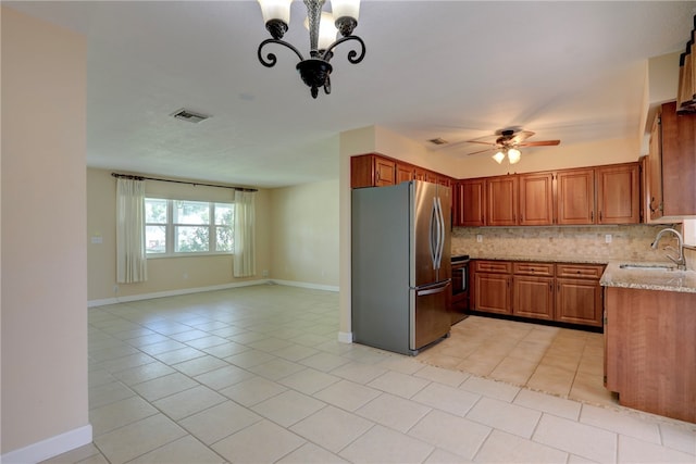 kitchen with light stone counters, sink, tasteful backsplash, light tile patterned floors, and stainless steel refrigerator