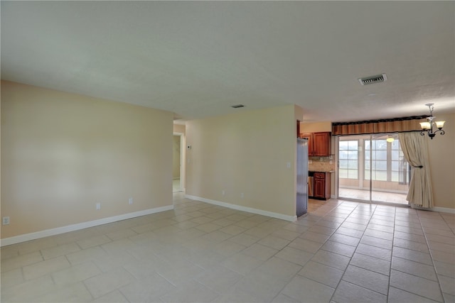 empty room with light tile patterned flooring and an inviting chandelier