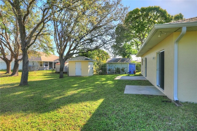 view of yard with a storage unit, an outbuilding, and fence