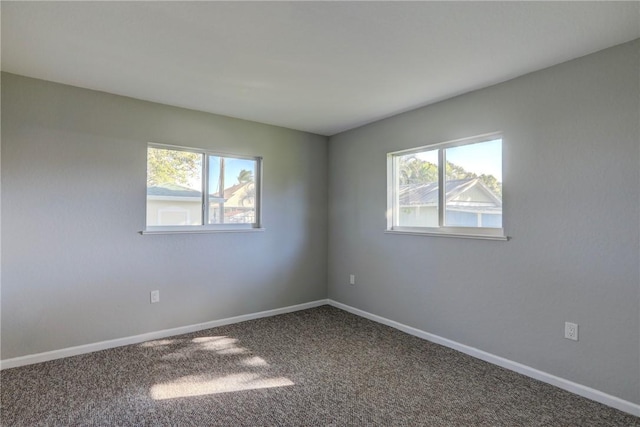 carpeted spare room with a healthy amount of sunlight and baseboards