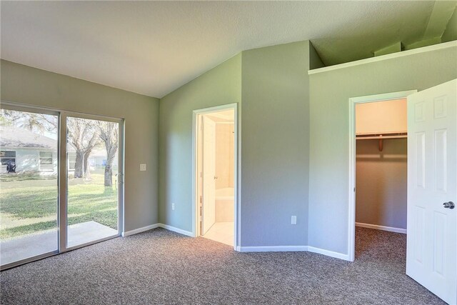 unfurnished bedroom featuring baseboards, carpet floors, vaulted ceiling, a spacious closet, and access to outside