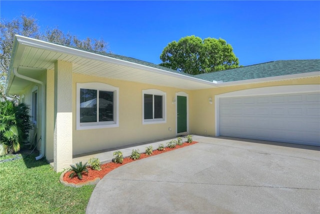 ranch-style house featuring a shingled roof, concrete driveway, a garage, and stucco siding