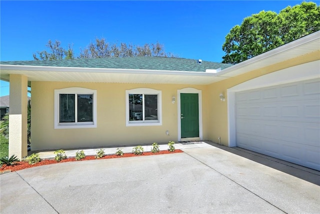 ranch-style home featuring stucco siding, an attached garage, driveway, and a shingled roof