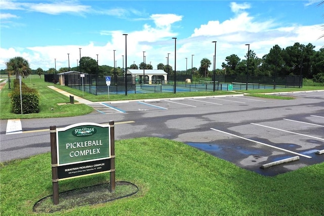 uncovered parking lot featuring a tennis court and fence