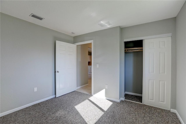 unfurnished bedroom with visible vents, baseboards, light colored carpet, and a closet