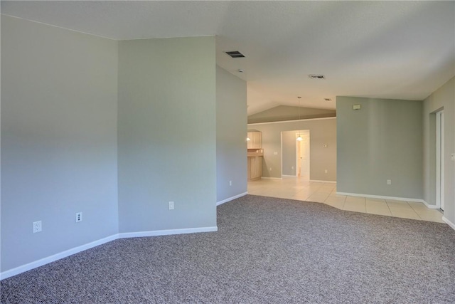 empty room with light carpet, visible vents, baseboards, and vaulted ceiling