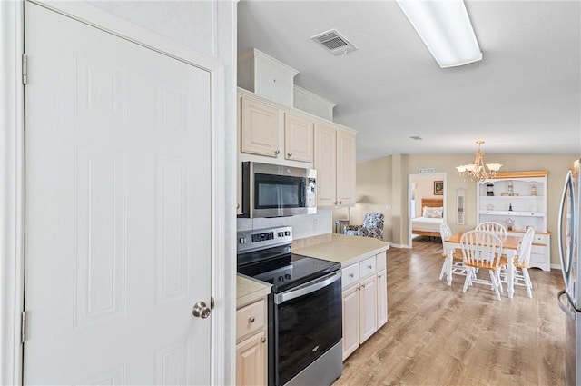 1218 Chipewa Dr, Sebastian, FL 32976 - kitchen with stainless steel appliances, a chandelier, light countertops, light wood-type flooring, and pendant lighting