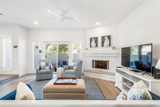 living area with a high end fireplace, recessed lighting, ceiling fan, and wood finished floors