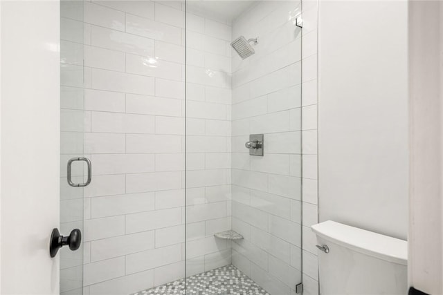 bathroom featuring toilet and a stall shower