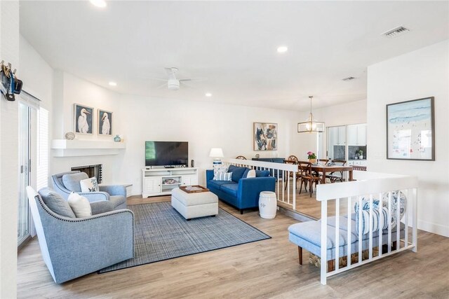 living area featuring visible vents, recessed lighting, a fireplace, wood finished floors, and a ceiling fan