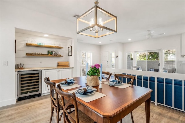 dining room featuring wine cooler, plenty of natural light, a bar, and light wood-style floors