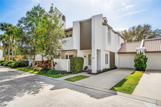 townhome / multi-family property with stucco siding, concrete driveway, an attached garage, and a tile roof