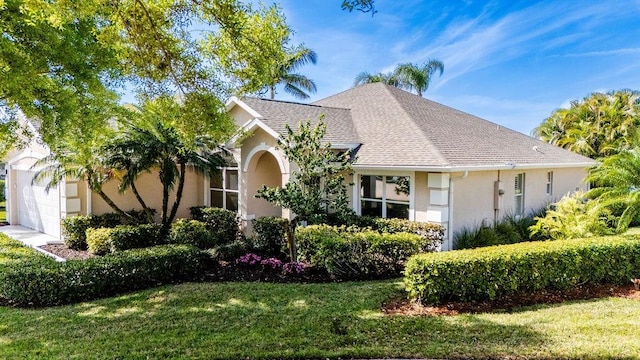 view of front of home featuring a garage, stucco siding, roof with shingles, and a front yard