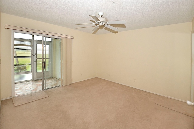 empty room with a textured ceiling, light colored carpet, and ceiling fan