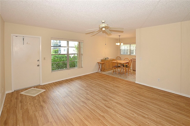 interior space featuring light hardwood / wood-style floors, ceiling fan with notable chandelier, and a textured ceiling