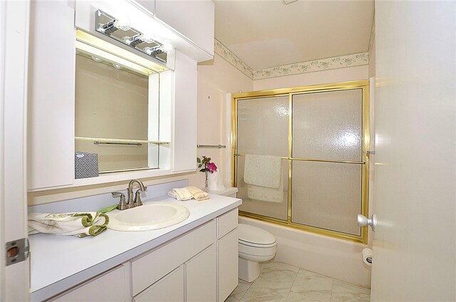 full bathroom featuring vanity, combined bath / shower with glass door, and toilet