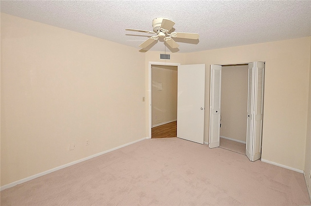 unfurnished bedroom with ceiling fan, a textured ceiling, and light colored carpet