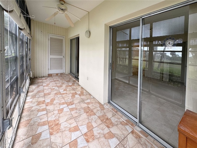 unfurnished sunroom featuring ceiling fan and plenty of natural light