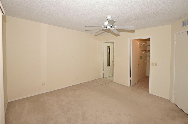 unfurnished bedroom with light colored carpet, a walk in closet, and a closet