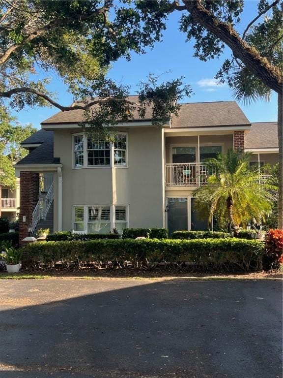 view of front of property featuring a balcony, stairs, and stucco siding