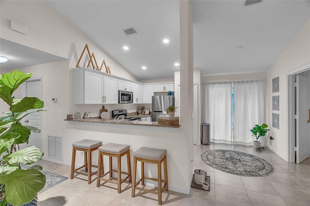 1360 18th Ave SW, Vero Beach, FL 32962 - kitchen featuring appliances with stainless steel finishes, white cabinetry, vaulted ceiling, light tile patterned floors, and a kitchen bar